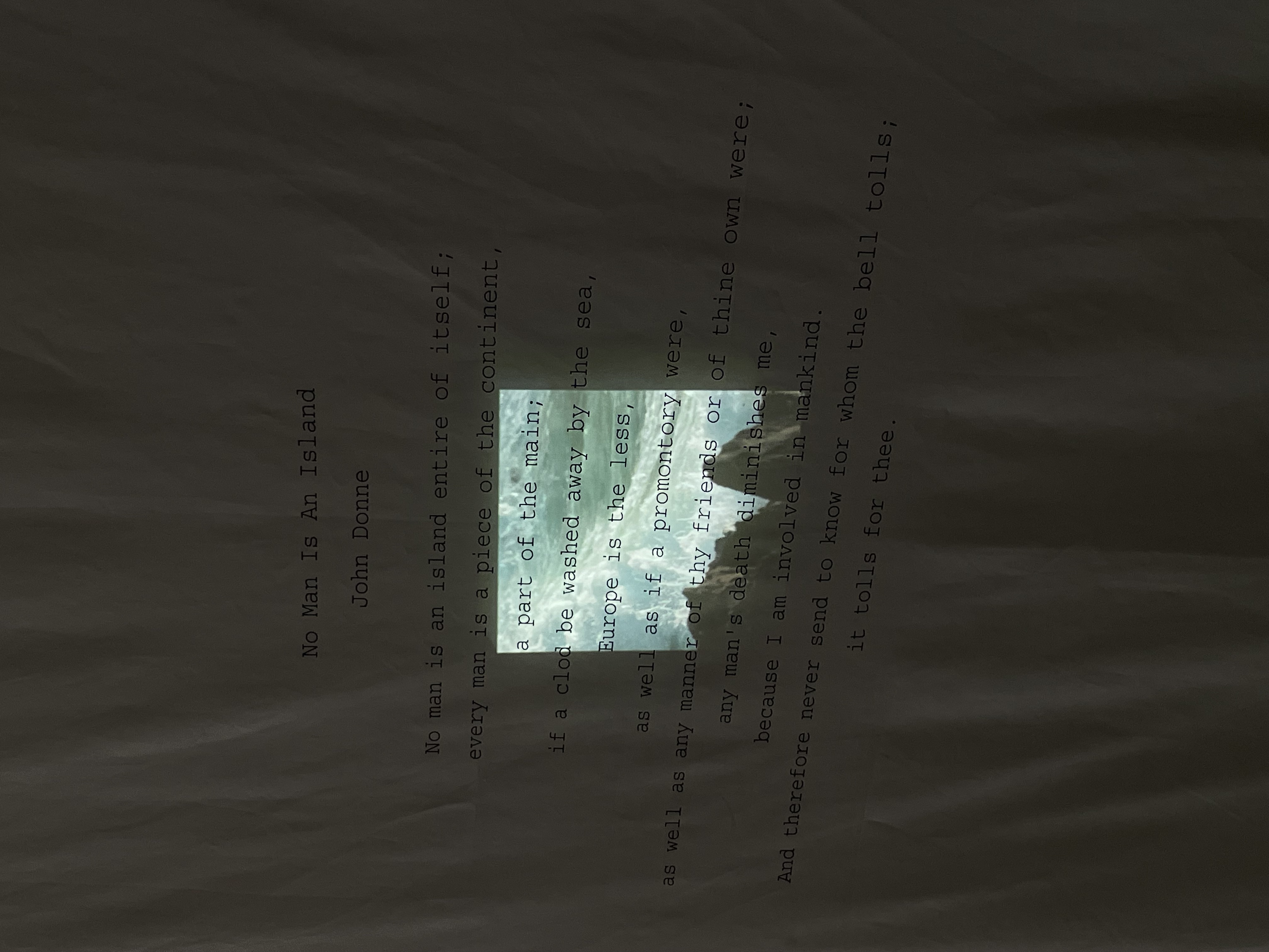 Projection installation of John Donne poem over crumpled surface
